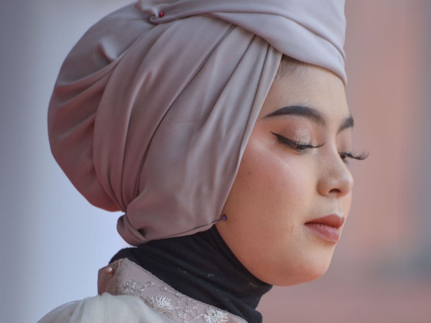 Femme portant un hijab en soie drapé couleur mauve, de profil
