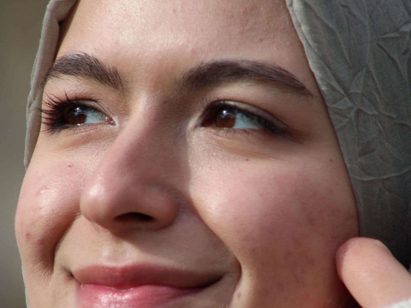 Femme souriante portant un hijab gris clair